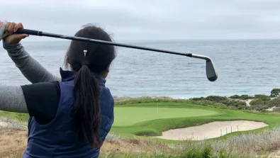 Camper hits iron tee shot with ocean view Nike Junior Golf Camps