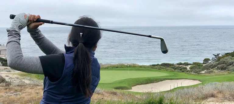 Camper hits iron tee shot with ocean view Nike Junior Golf Camps