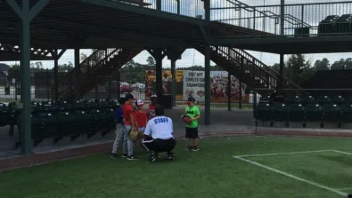Coach squats to speak with group of campers at Scrap Yard Sports baseball fields