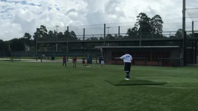 Coach on pitchers mound directing campers at first base
