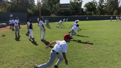 Athletes running in the outfield during baseball camp