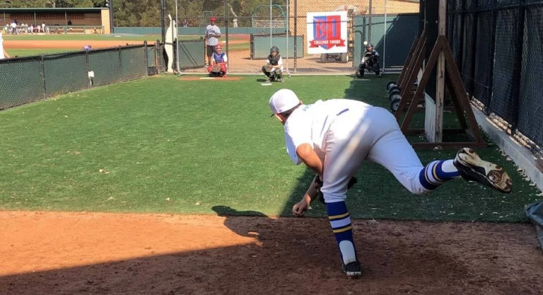 Baseball pitcher follows through on throw to catcher in bullpen