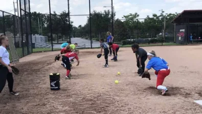 Softball players practice fielding in partners