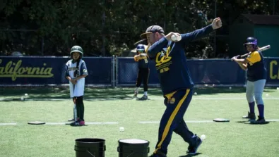 Cal Softball Coach Demonstrating Swing to onlooking campers