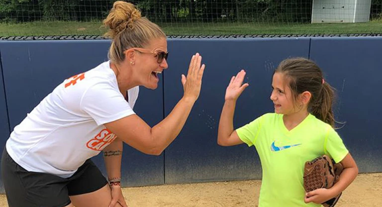 Coach and camper high five in front of backstop
