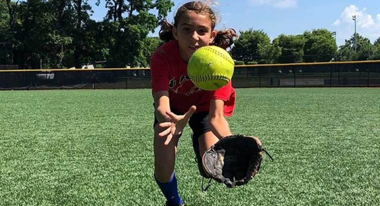 Softball camper dives to catch a ball in the outfield